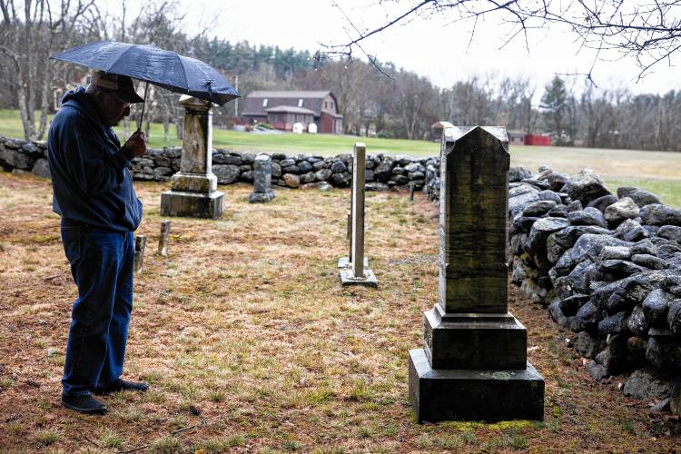 Norm Yeaton looks over a grave marker in the private Yeaton cemetery off of Black Hill Road in Epsom.