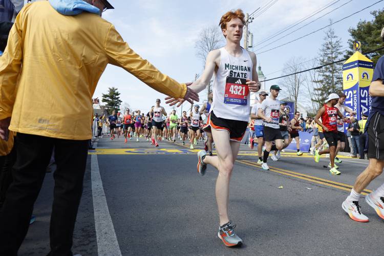 Zachary Helner, of Michigan, gives a high-five to a volunteer as he breaks from the start of the Boston Marathon, Monday, April 15, 2024, in Hopkinton, Mass. (AP Photo/Mary Schwalm)