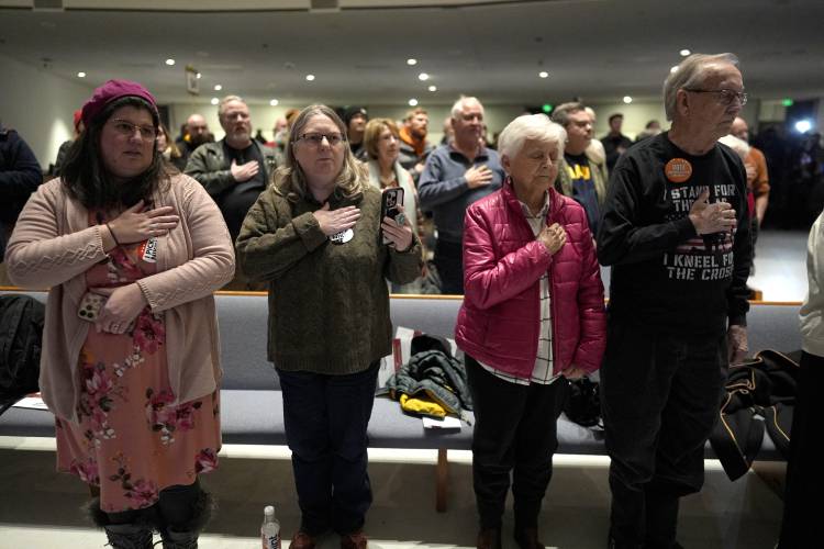 Voters recite the Pledge of Allegiance at a caucus site at Franklin Junior High in Des Moines, Iowa, Monday, Jan. 15, 2024. (AP Photo/Carolyn Kaster)