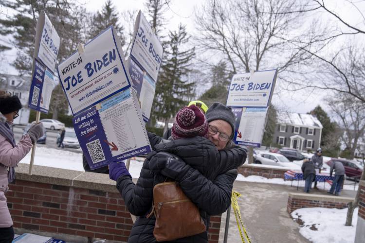 Sarah Sigel, right, embraces fellow supporter of President Joe Biden, Carol Czaja, as they campaign for his write-in ballot in the New Hampshire presidential primary outside a polling site in Manchester, N.H., Tuesday, Jan. 23, 2024. (AP Photo/David Goldman)