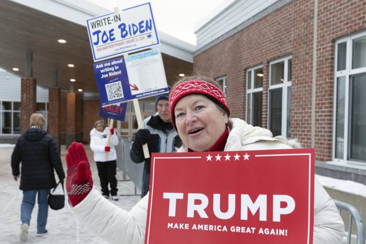 Tina Lorenz, right, and Ed Schoen, behind, hold candidate signs outside the polling place at Windham High School in the presidential primary election, Tuesday, Jan. 23, 2024, in Windham, N.H. (AP Photo/Michael Dwyer)